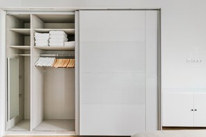 Een inloopkast met planken, kledingroede en een spiegel.