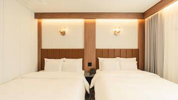 A hotel room with two beds, a wooden headboard, a nightstand, and a telephone.