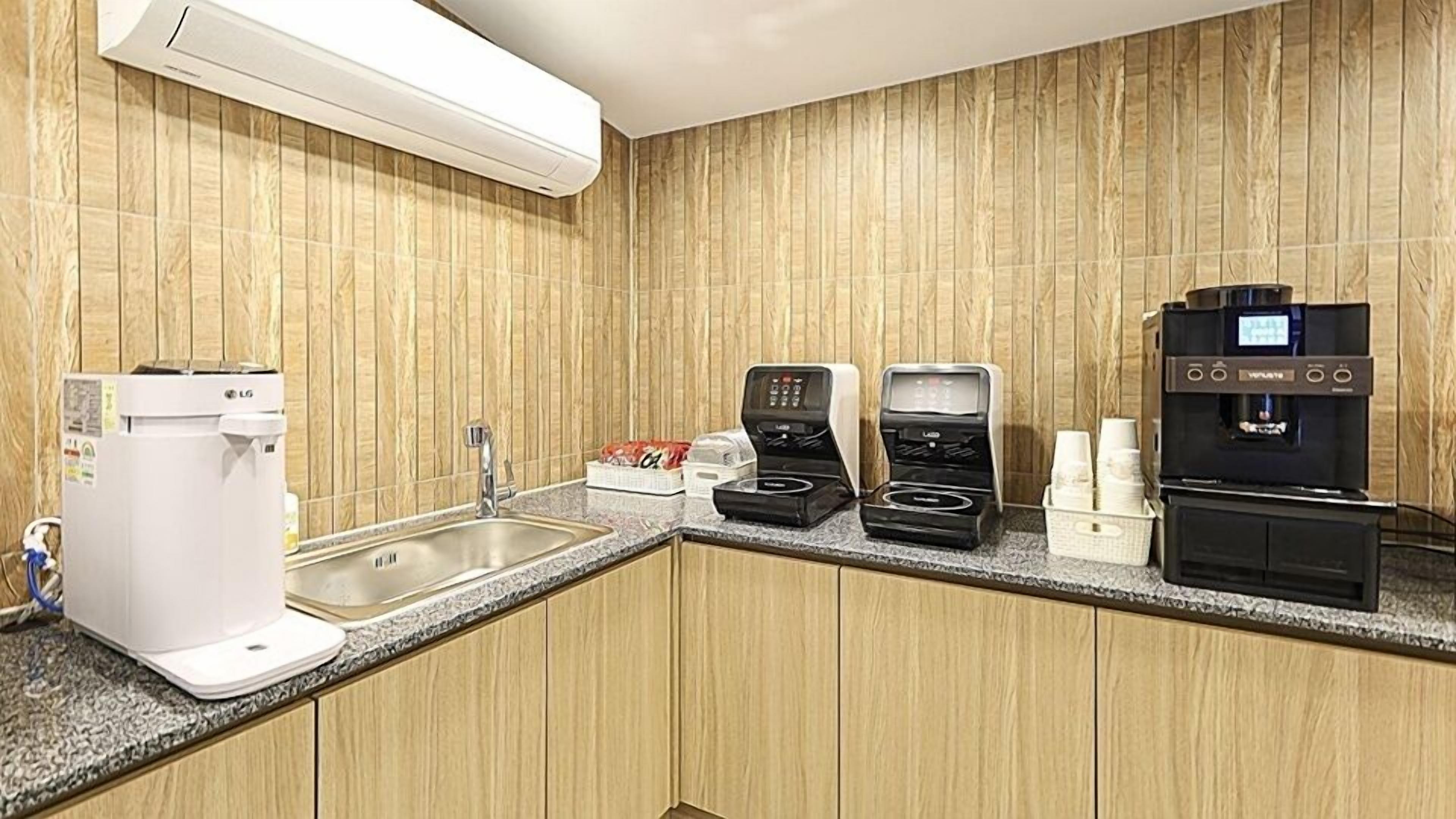 Uma cozinha compacta com máquina de café, chaleira e dispensador de café.