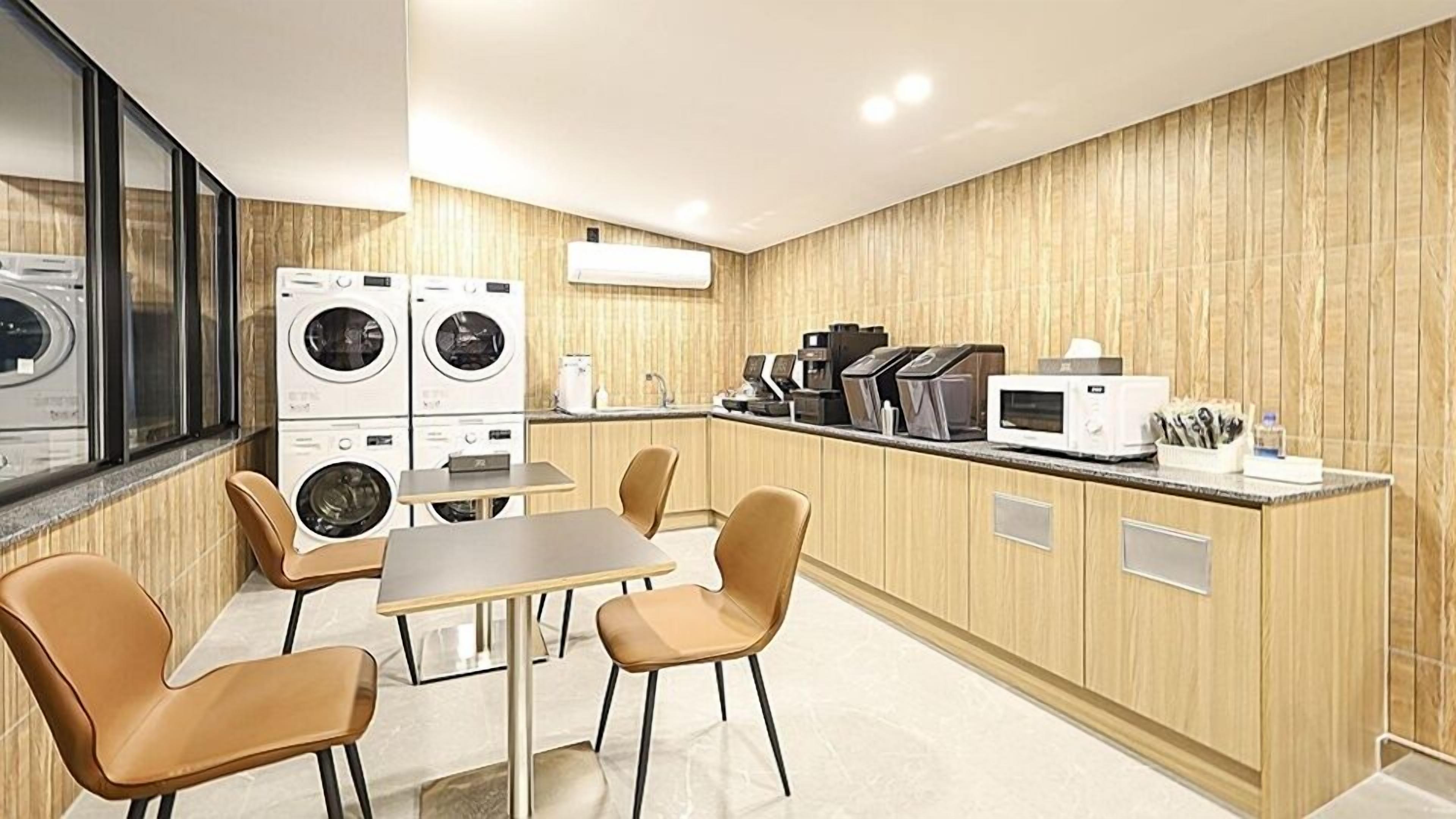 A modern kitchen with built-in appliances, a dining area with chairs, and a large window.
