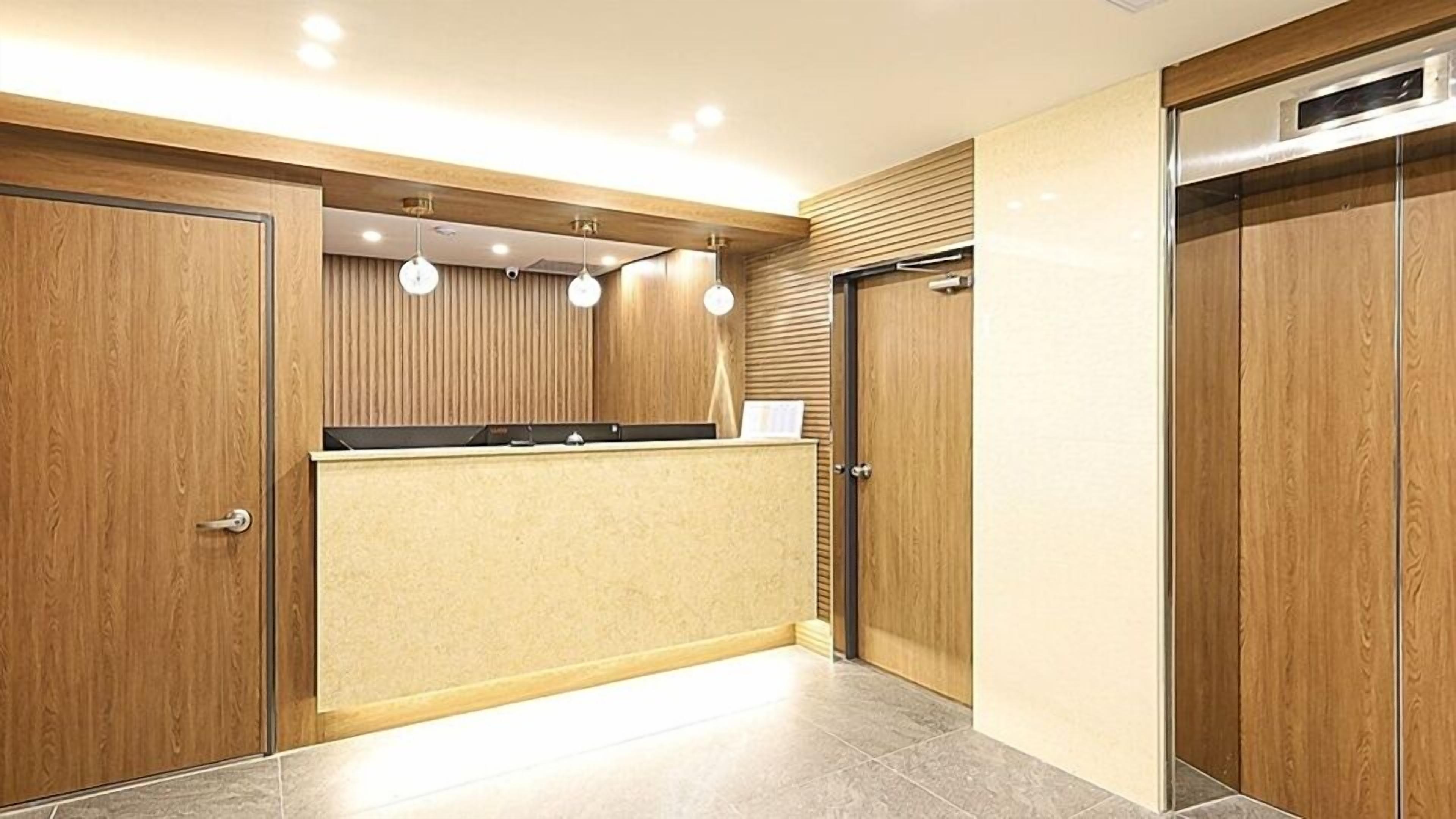 A modern reception area with wooden paneling, a reception desk, and a glass partition.