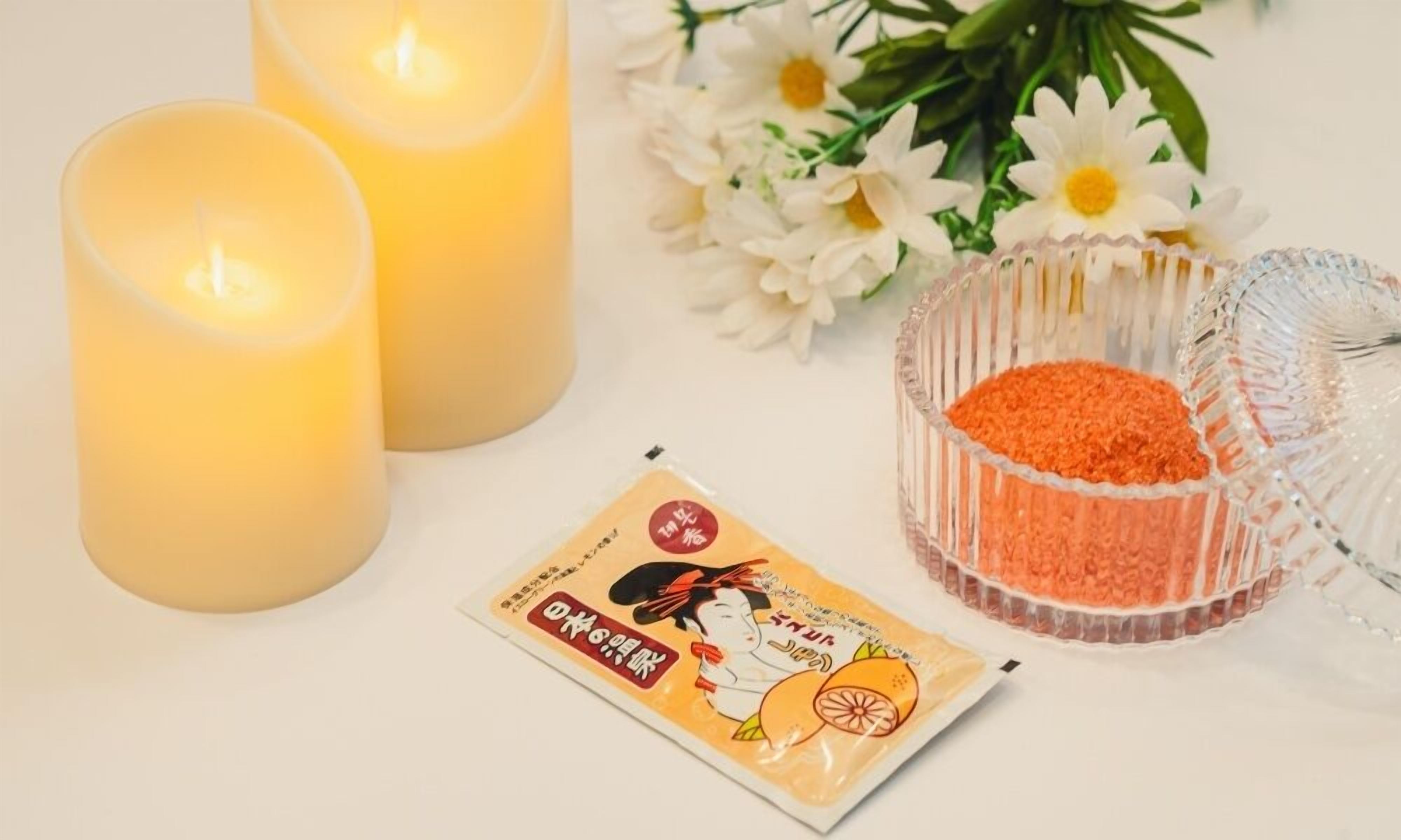 Zwei brennende Kerzen, eine Tüte Snacks und eine Schale mit roter Füllung.