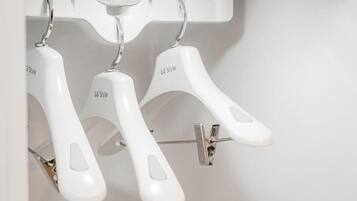 Three white LG Styler hangers hanging from a metal rod.