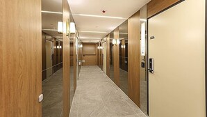 A hotel corridor with wooden doors, a tiled floor, and wall-mounted lighting. - Cheonan Asan Rosy Hotel (Asan)