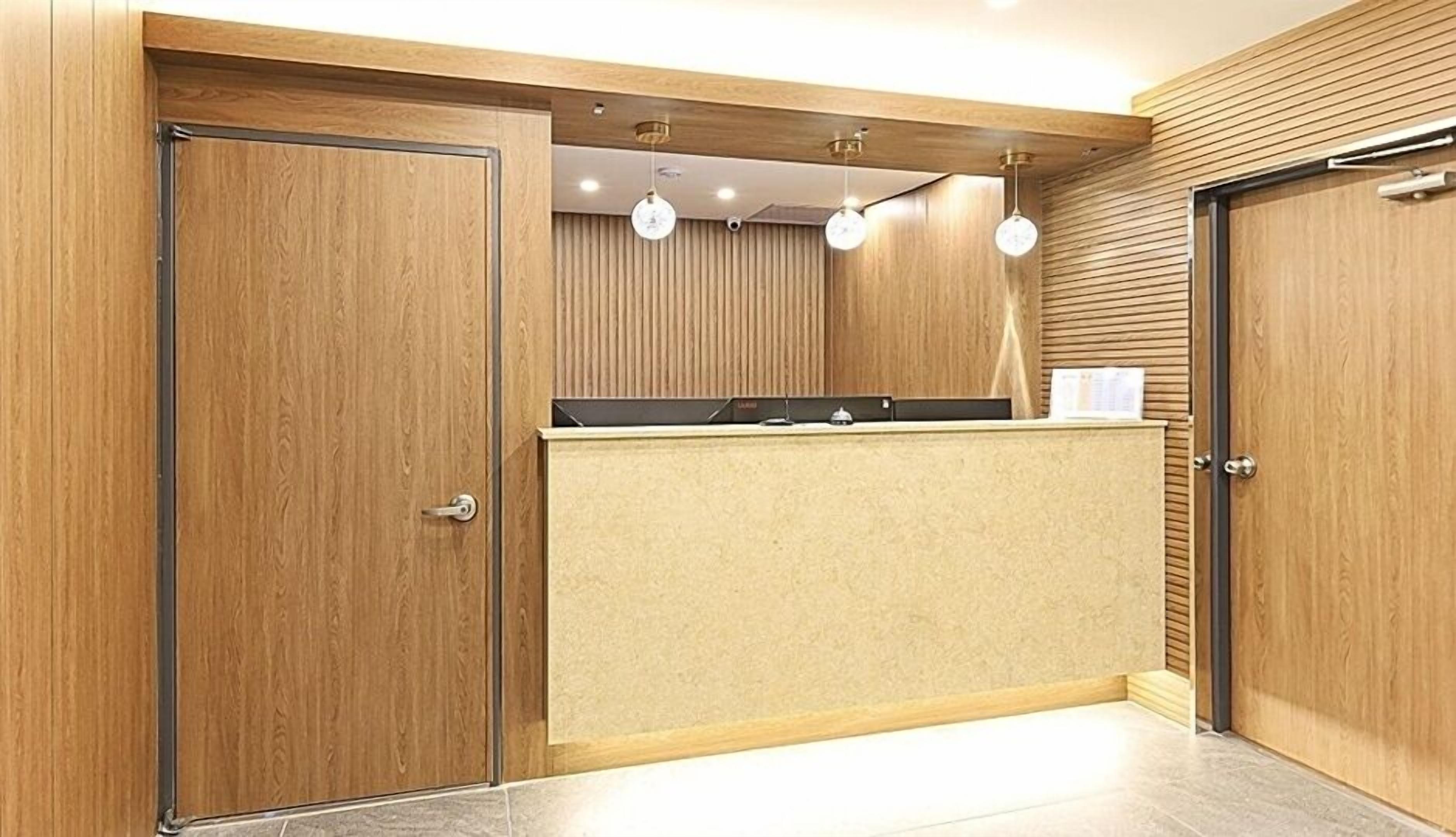 A reception area with wooden paneling, a reception desk, and three pendant lights.