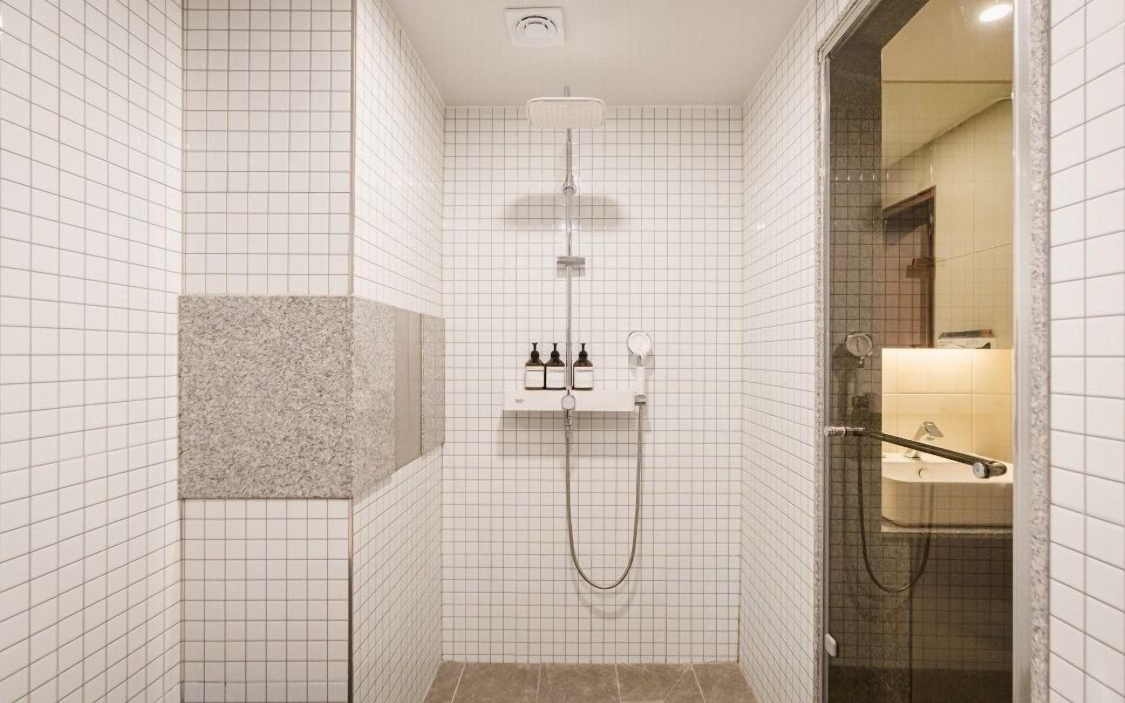 A modern bathroom with a shower, a vanity with a mirror, and a towel rack.