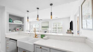 A modern kitchen with white countertops, a built-in dishwasher, and pendant lighting. - Rosemary Luxe - steps from restaurants/shops with access to community pools, fitness, and tennis! (Rosemary Beach)