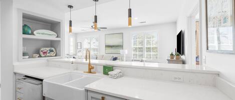 A modern kitchen with white countertops, a built-in dishwasher, and pendant lighting.