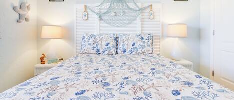 A bedroom with a floral bedspread, a hanging net, and two wall-mounted lamps.