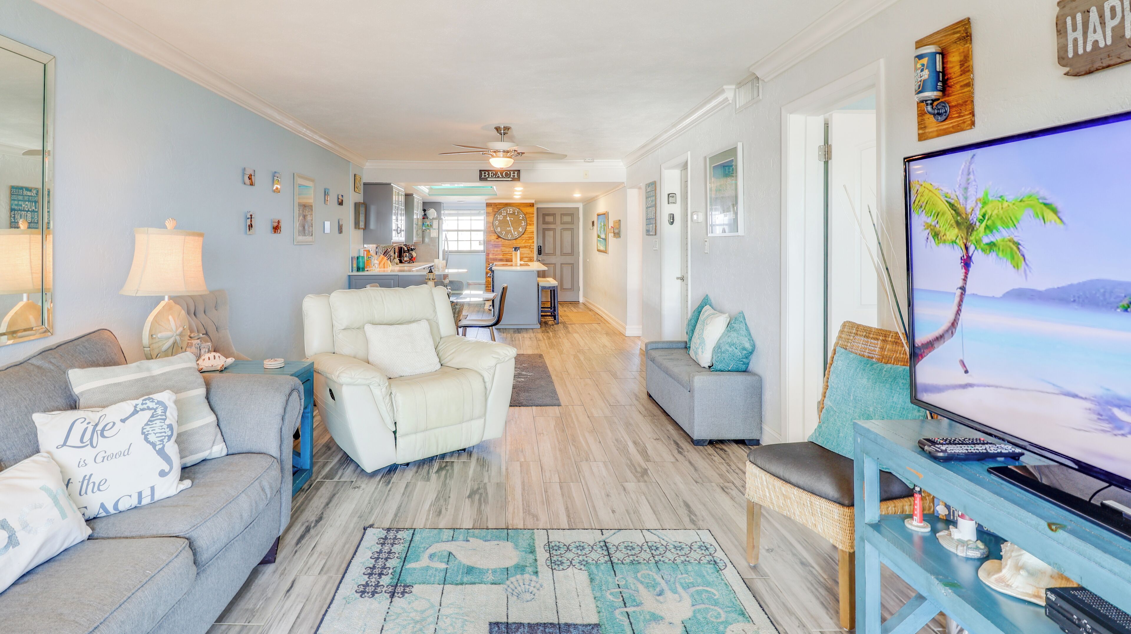 A spacious living room with a television, sofas, and a kitchen in the background.