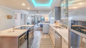 Uma cozinha moderna com eletrodomésticos de aço inoxidável, uma ilha central e vista para a sala de estar.