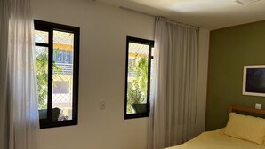 Un dormitorio con dos ventanas, una cama y un cuadro colgado en la pared.
