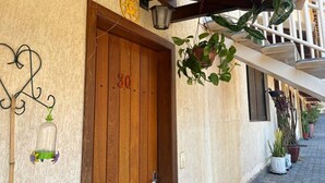 Una puerta de madera con el número 30, un farol colgante y plantas en macetas en la fachada de un edificio.