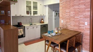 Una cocina con armarios blancos, una mesa de madera y una pared de ladrillo decorativa.