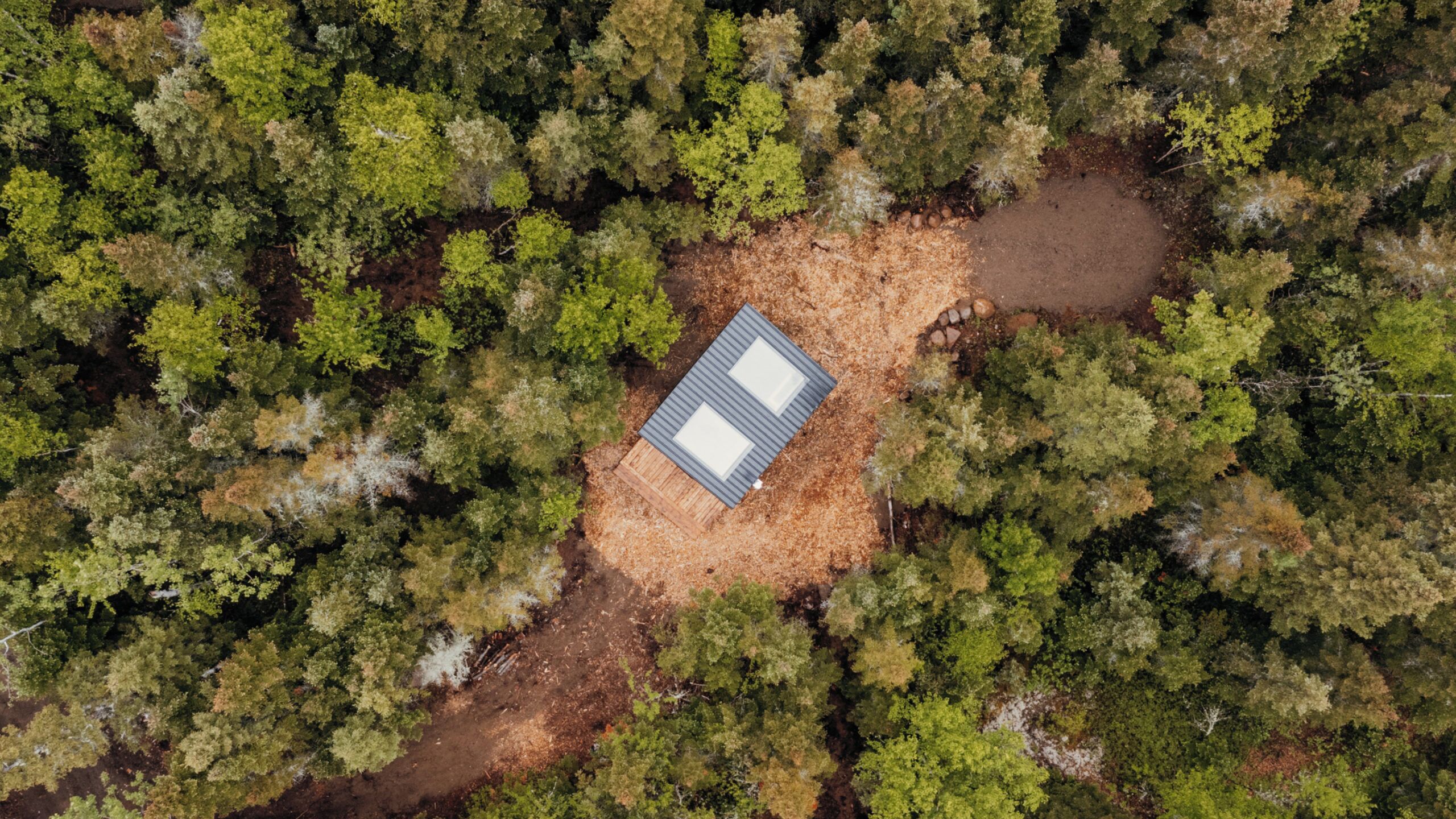 Eine Luftaufnahme zeigt eine Hütte, umgeben von dichtem Wald.