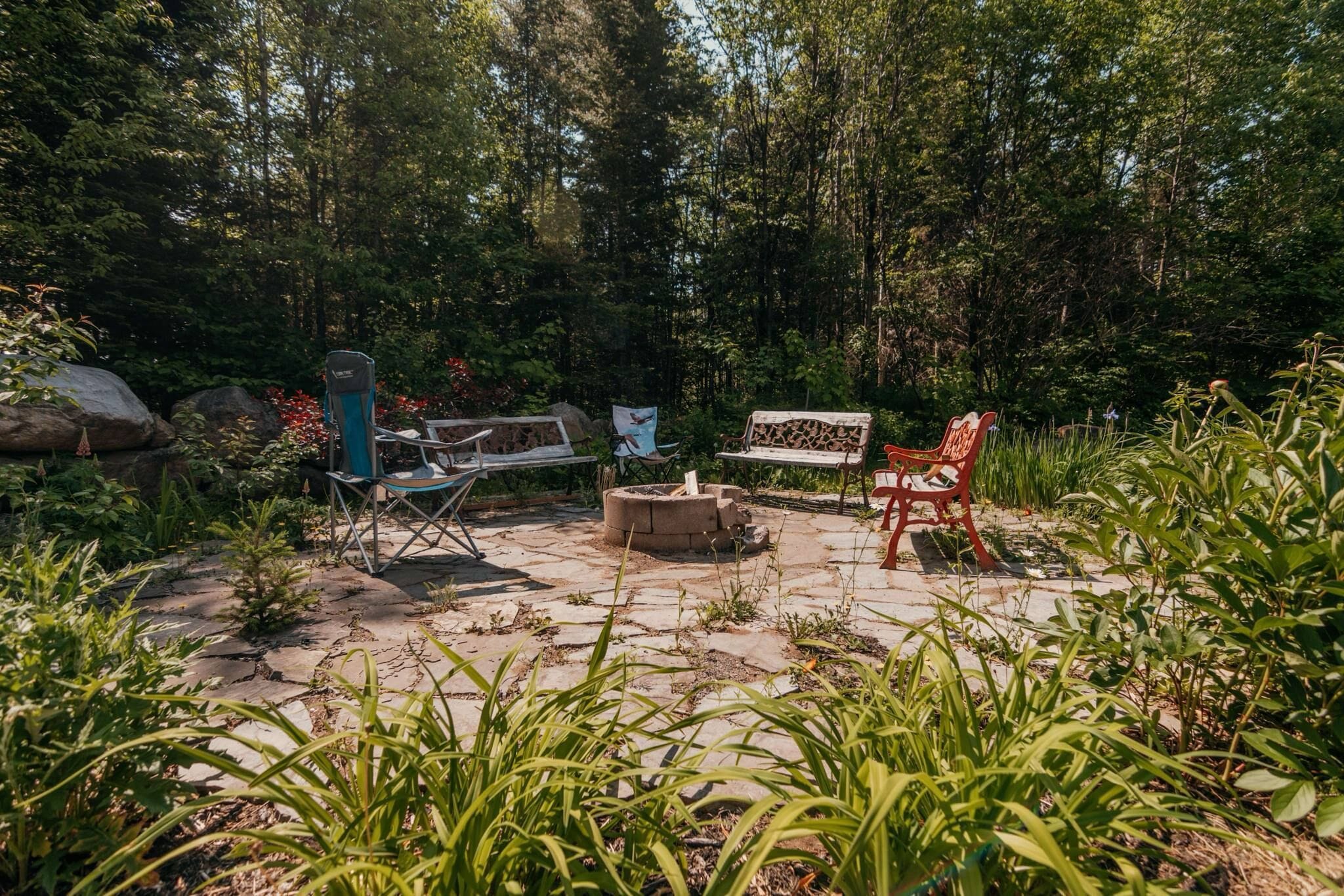 An outdoor patio area with a fire pit, a bench, and a chair.