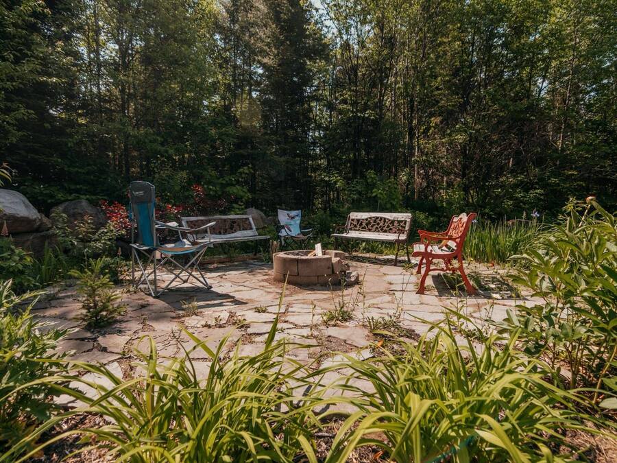 An outdoor patio area with a fire pit, a bench, and a chair.