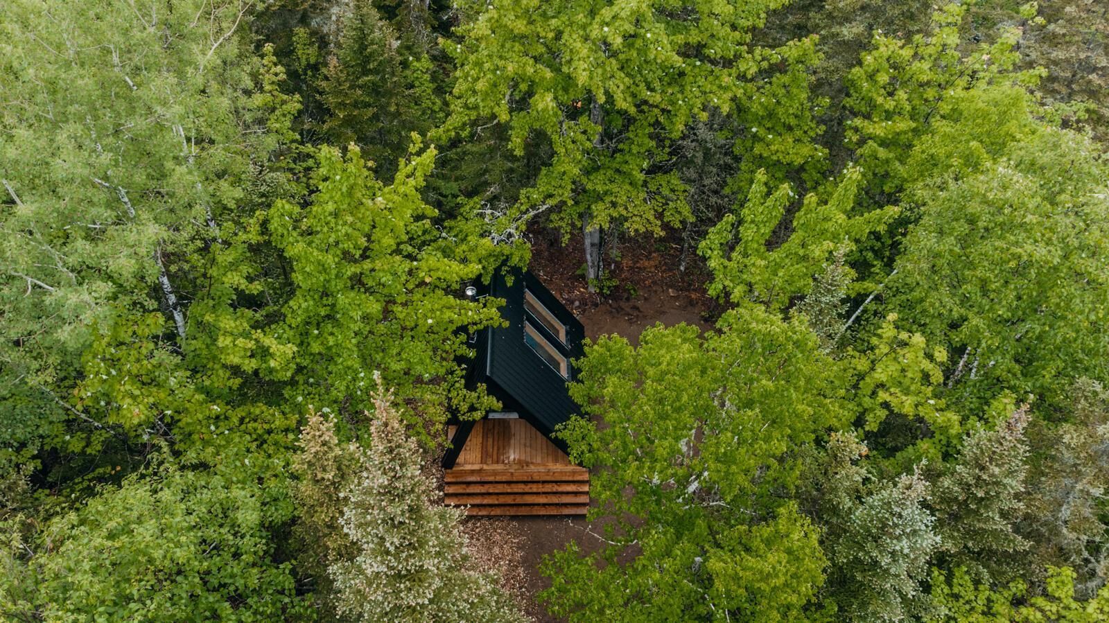 Vue aérienne d’une cabane entourée d’une forêt dense.