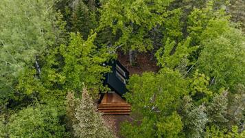 Vue aérienne d’une cabane entourée d’une forêt dense.