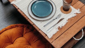 A wooden dining table with two blue plates, a white placemat, and two glass cups. - Domaine à Ciel Ouvert (La Malbaie)