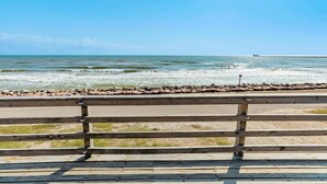 A wooden bench overlooking a beach with a rocky shoreline and calm sea. - Breakers Edge - Waterfront, 8 Sides of Sunshine! (Surfside Beach)