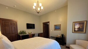 A hotel room with a large bed, a desk, a chair, a television, and a painting on the wall. - Charleston House Bed & Breakfast Inn (Charleston)