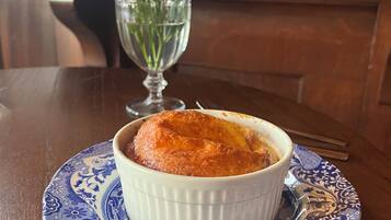 A dessert in a white ramekin on a blue and white patterned plate, with a fork beside it on a wooden table.