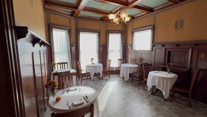 A dining area with round tables, chairs, and a chandelier. - Charleston House Bed & Breakfast Inn (Charleston)