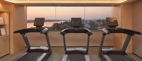 Un gimnasio con tres cintas de correr, vista a la ciudad y paredes de madera.