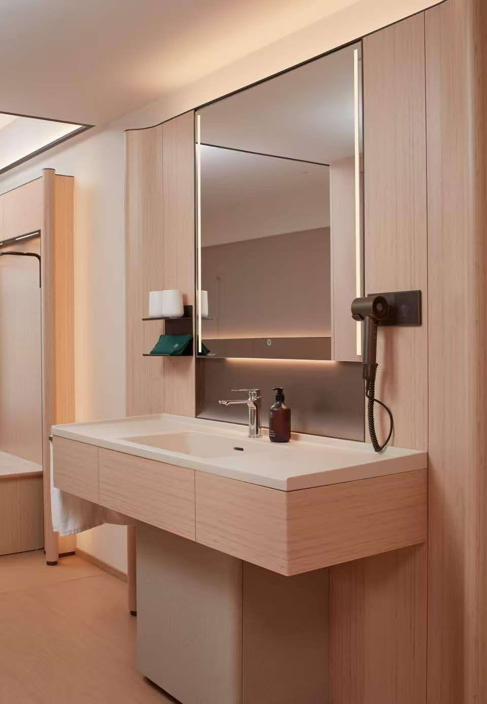Une salle de bain moderne avec un grand miroir, un lavabo et un porte-serviettes.