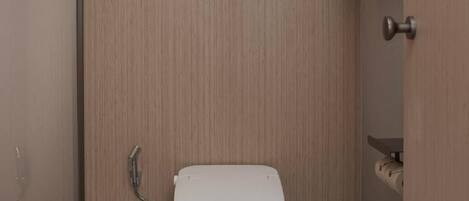 Un baño moderno con un inodoro blanco, un cepillo de bambú y una toalla colgada en un perchero.