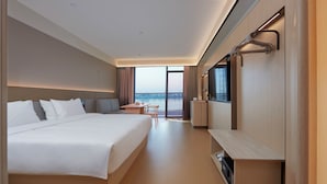 Habitació d'hotel moderna amb un llit gran, escriptori, televisió de pantalla plana i vistes a l'aigua.