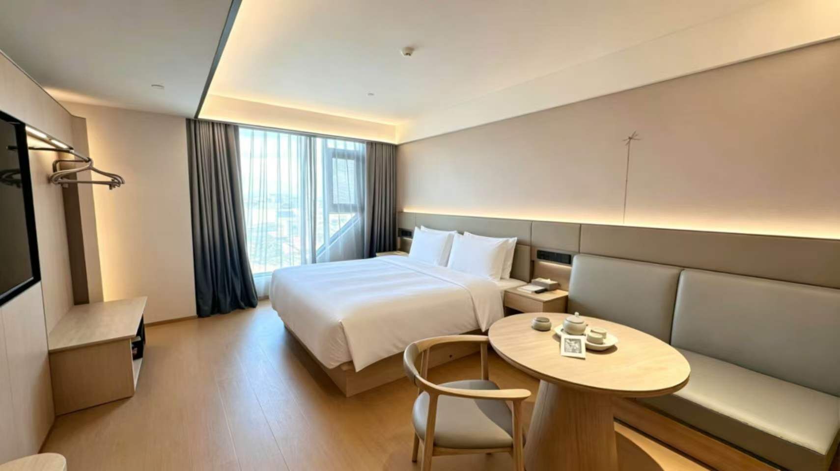 Une chambre d’hôtel moderne avec un grand lit, une table de salle à manger ronde, un canapé et un bureau.