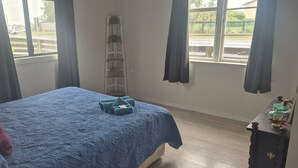A bedroom with a bed, a nightstand, a window, and a view of the outside. - cheap and affordable  (Te Kōpuru)