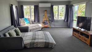 A modern living room with a sofa, a TV, and a wooden ladder. - cheap and affordable  (Te Kōpuru)