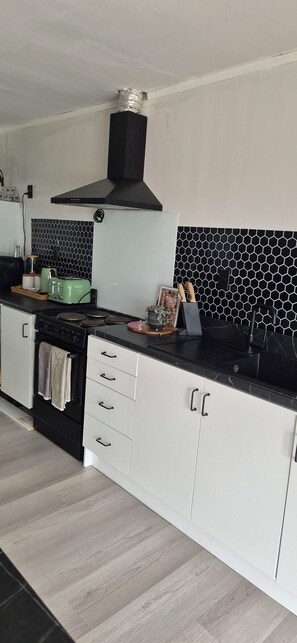 Una cocina moderna con armarios blancos, encimera negra y salpicadero con azulejos hexagonales.