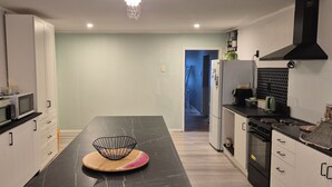 A modern kitchen with white cabinets, a black countertop, and a microwave. - cheap and affordable  (Te Kōpuru)