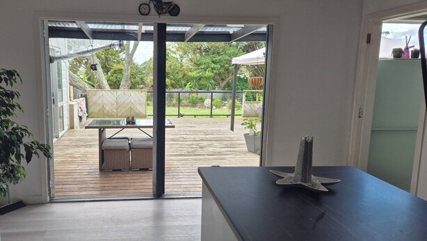A modern kitchen with a sliding glass door leading to an outdoor deck. - cheap and affordable  (Te Kōpuru)