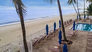 Zona de piscina frente al mar con sillones y sombrillas.