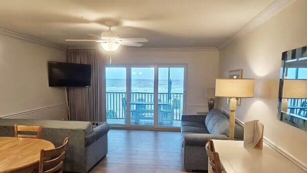 Una sala de estar con balcón, televisor de pantalla plana, mesa de comedor y sofá.