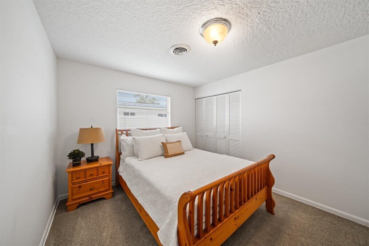 Une chambre à coucher avec un lit en bois, une table de chevet avec une lampe et une fenêtre avec des stores.