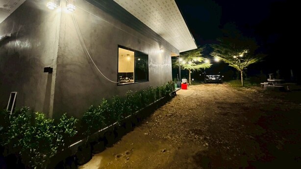 A modern building with a large window and a covered outdoor area with a dirt path. - Wangnue Mountain View Resort&Hotel (Wang Nuea)