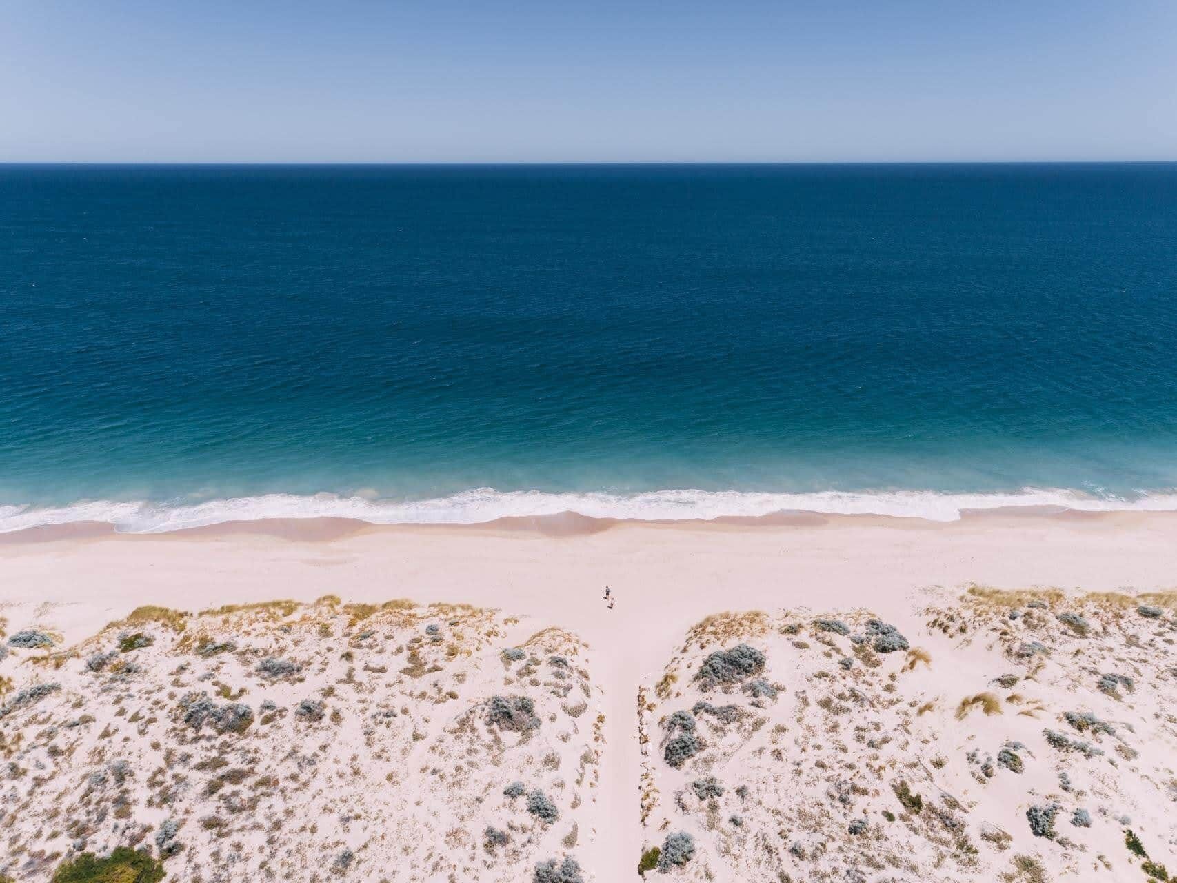 A beach with a clear view of the ocean and sandy dunes.