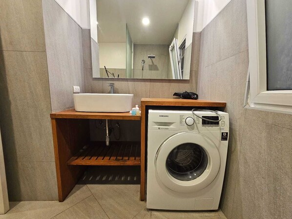 Une petite salle de bain équipée d’un lavabo, d’un miroir et d’un lave-linge à chargement frontal.