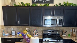 A kitchen with dark cabinets, a granite countertop, a microwave, a stove, and a sign that says "Let's Eat". - Luxury 4-bedroom house with Pool and Entertainment Room Near Airport (Las Vegas)