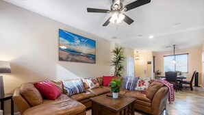 A spacious living room with a brown leather sofa set, a wooden coffee table, and a ceiling fan. - Luxury 4-bedroom house with Pool and Entertainment Room Near Airport (Las Vegas)