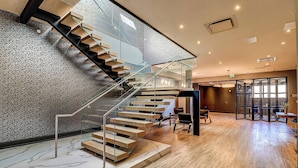 A modern interior with a glass staircase, wooden flooring, and a patterned wall. - Dream Suites Near YYZ Airport (Mississauga)