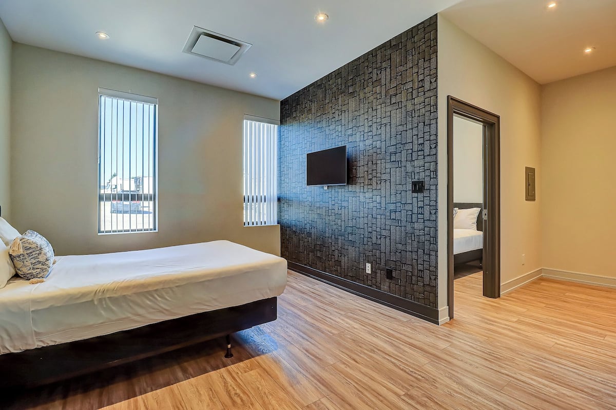 Una camera da letto moderna con un letto, una TV a parete e un pavimento in legno.