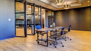 A conference room with a wooden table, blue chairs, and glass doors leading to a staircase. - Dream Suites Near YYZ Airport (Mississauga)