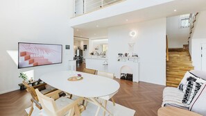 Un grand espace de vie comprenant une table à manger, des chaises, un téléviseur et une cuisine en arrière-plan.